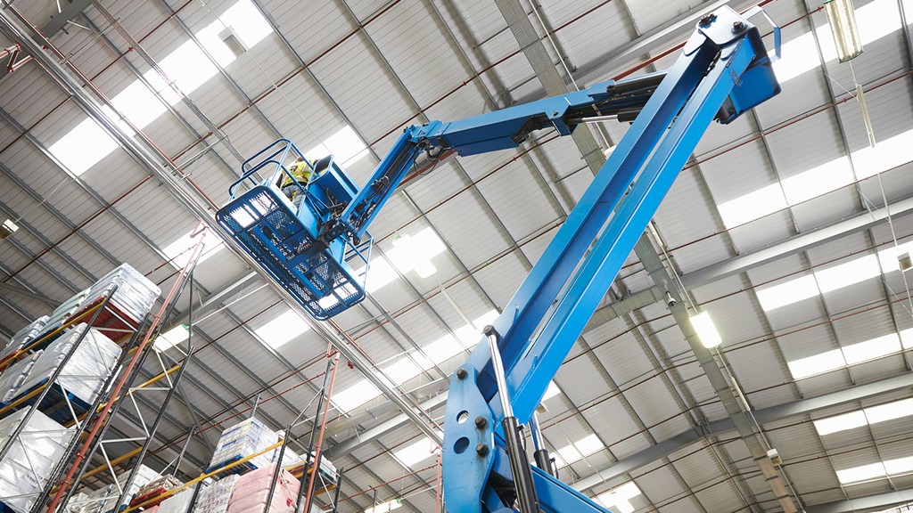an operator using an articulated cherry picker to install racking in a warehouse