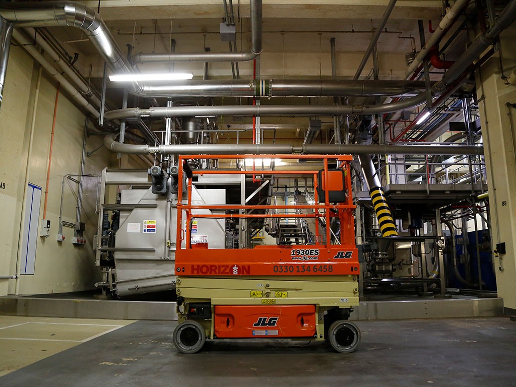An electric JLG 1930 ES scissor lift being used for indoor maintenance work 
