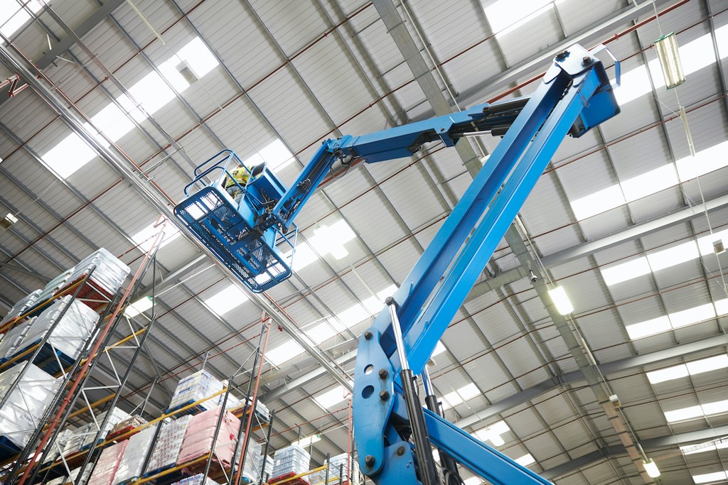 Boom Lift inside a warehouse next to pallet racking
